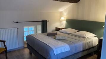 Une chambre à coucher comprenant un lit, une table de chevet, une lampe, une fenêtre et un radiateur.