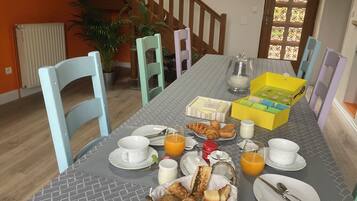 A breakfast setup with a table, chairs, breakfast items, and a staircase in the background.