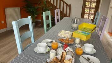 Una mesa con sillas y comida para el desayuno.