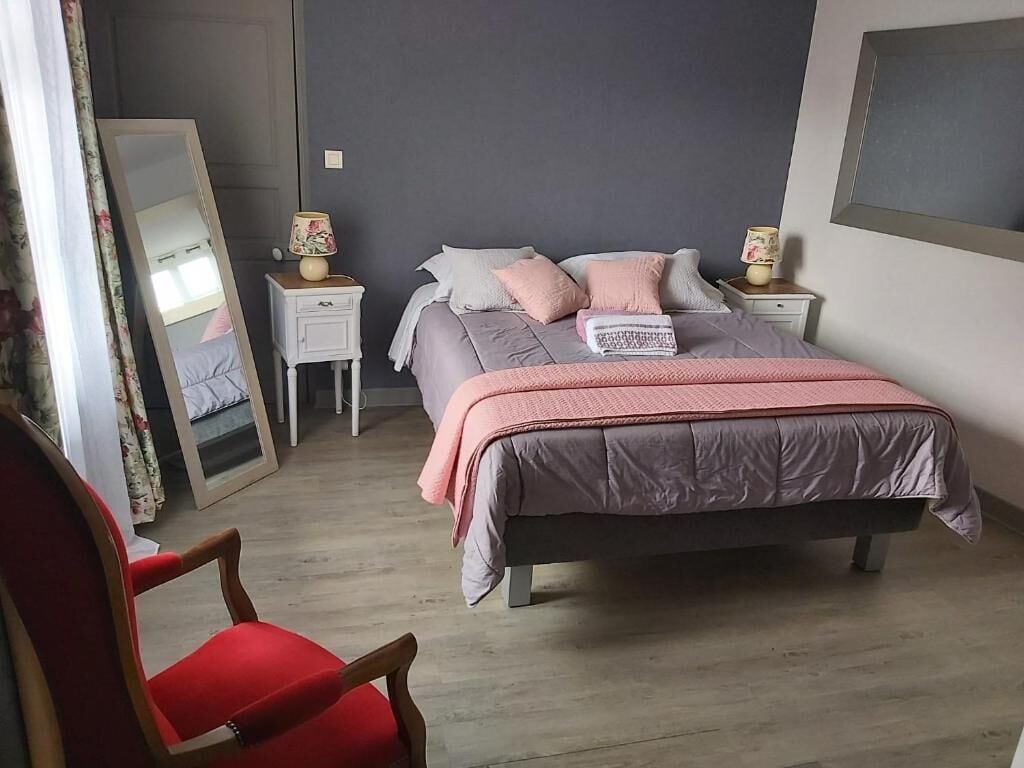 A bedroom with a bed, nightstands, a mirror, a chair, and a dresser.