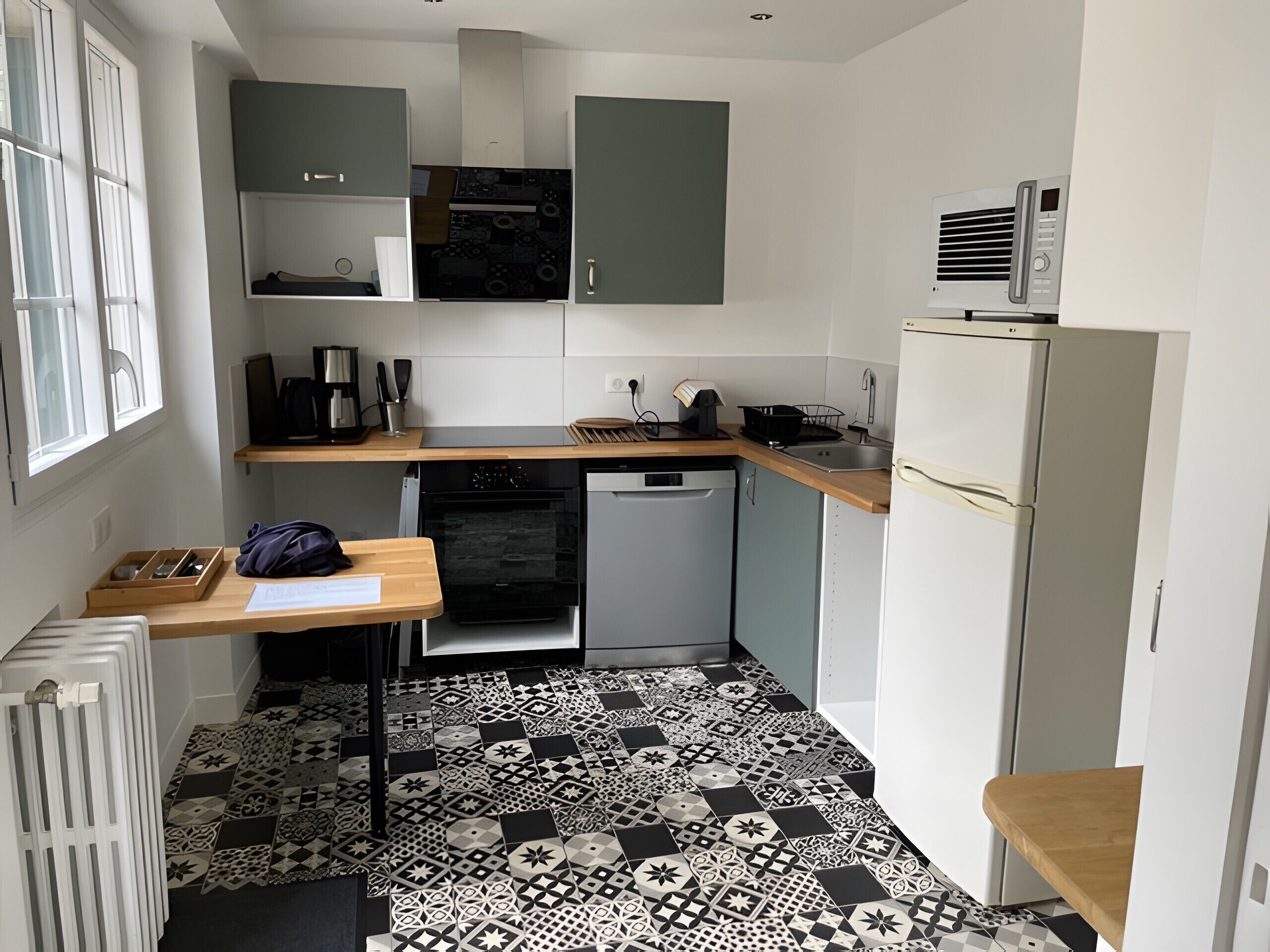 A compact kitchen with a dishwasher, oven, and a microwave on the countertop.