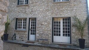 Un edificio de piedra con dos ventanas, una puerta y un banco en el exterior.