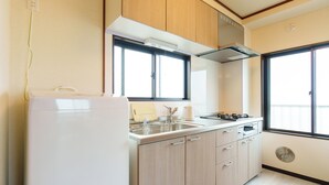 Una cucina con frigorifero, lavello, fornello e mobili impiallacciati in legno.
