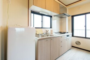 Uma cozinha equipada com geladeira, pia, fogão e armários de madeira.