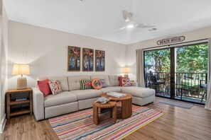 Ein Wohnzimmer mit einer Couch, zwei Lampen, einem Couchtisch und Blick auf einen Balkon.