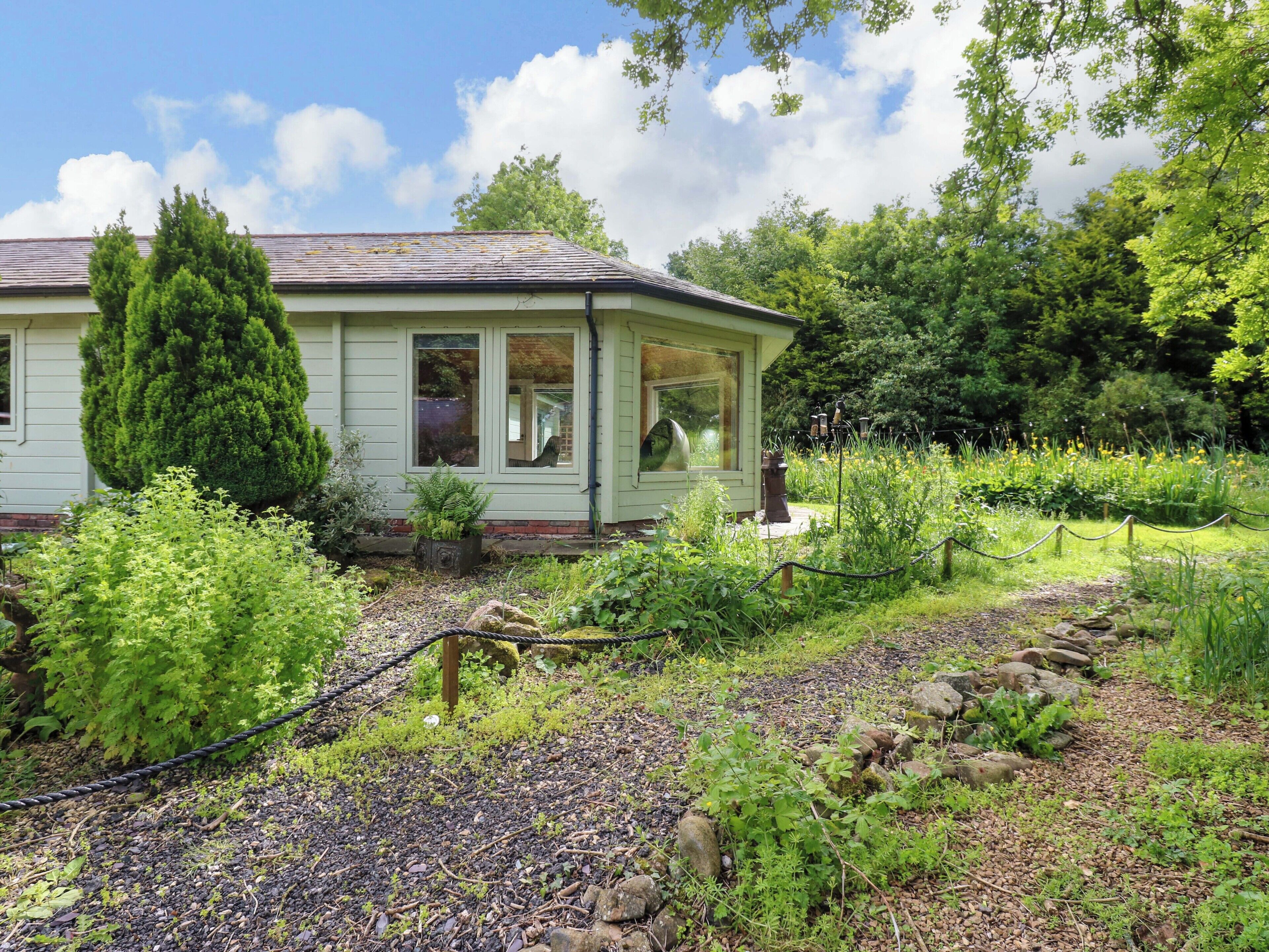 A house with a garden, a large tree, and a fence.