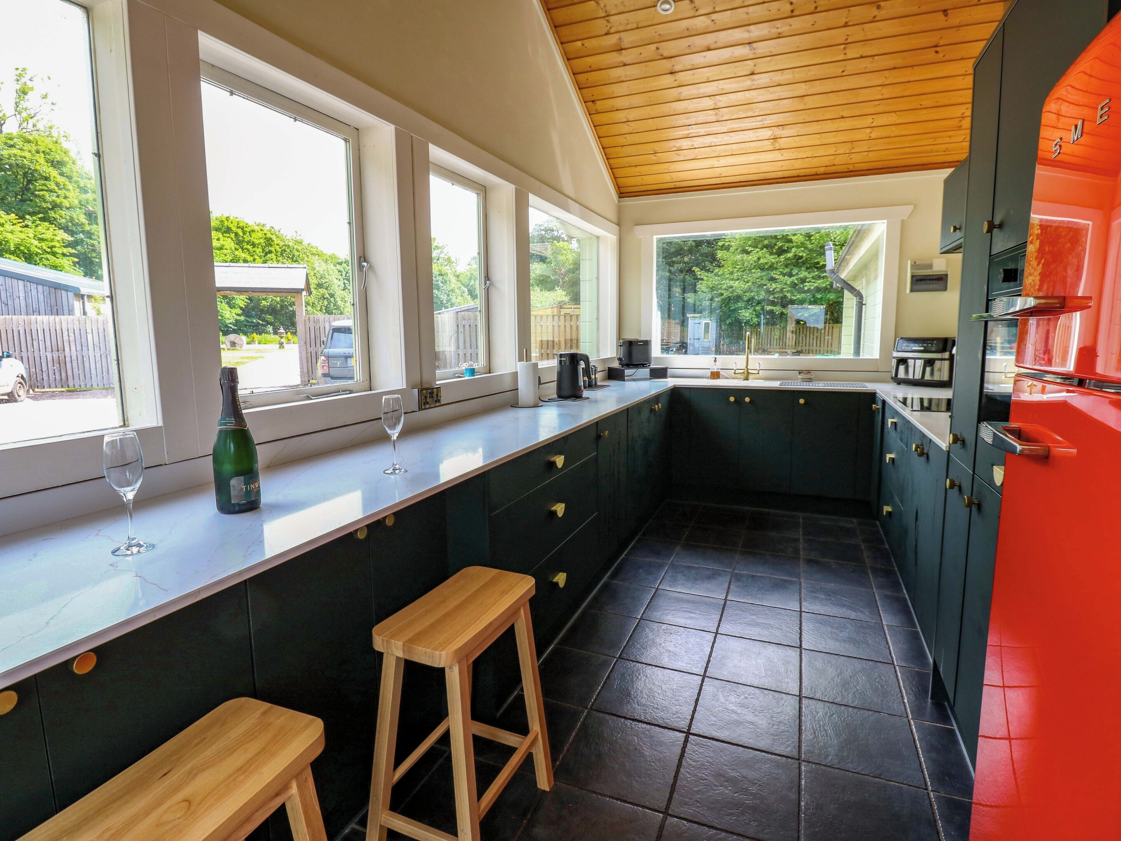 Una cocina con barra, ventanas amplias y un electrodoméstico rojo.