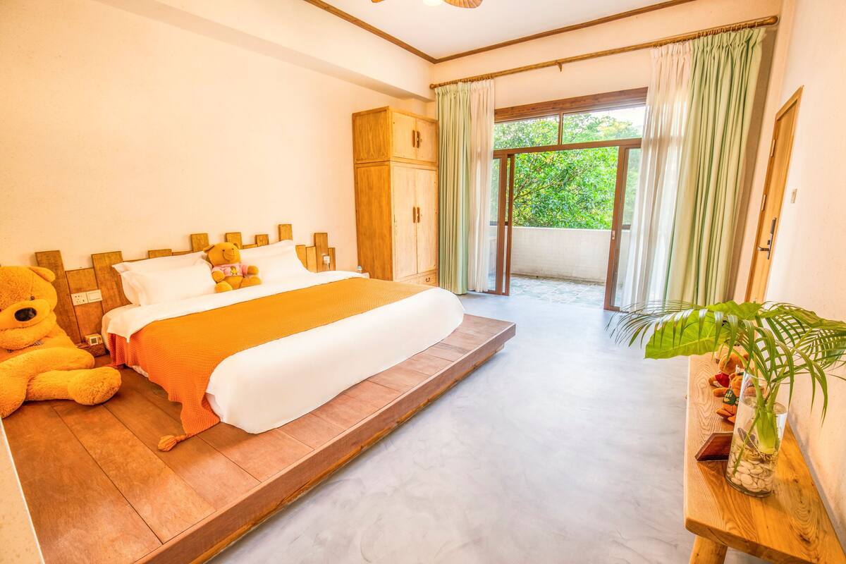 A bedroom with a bed, a wardrobe, a window with curtains, and a plant on a table.