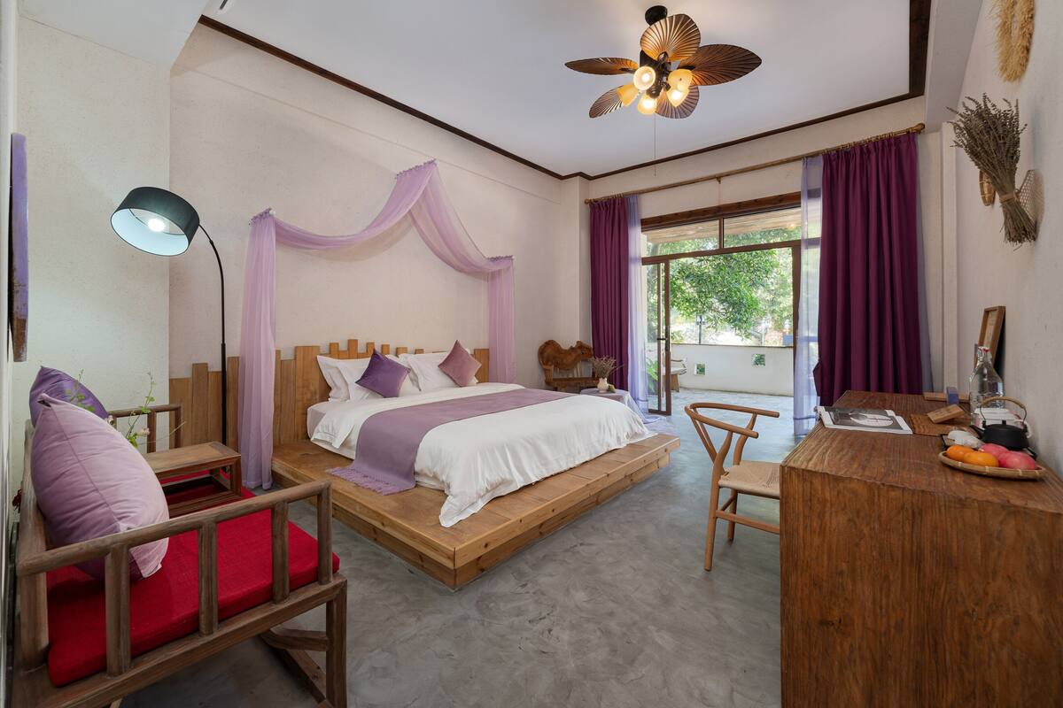 A bedroom with a bed, bedside table, chair, and a small desk with a lamp.