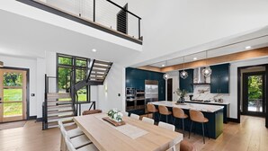 A modern kitchen with dark cabinets, stainless steel appliances, and a central island. - Willow Landing (Troutman)