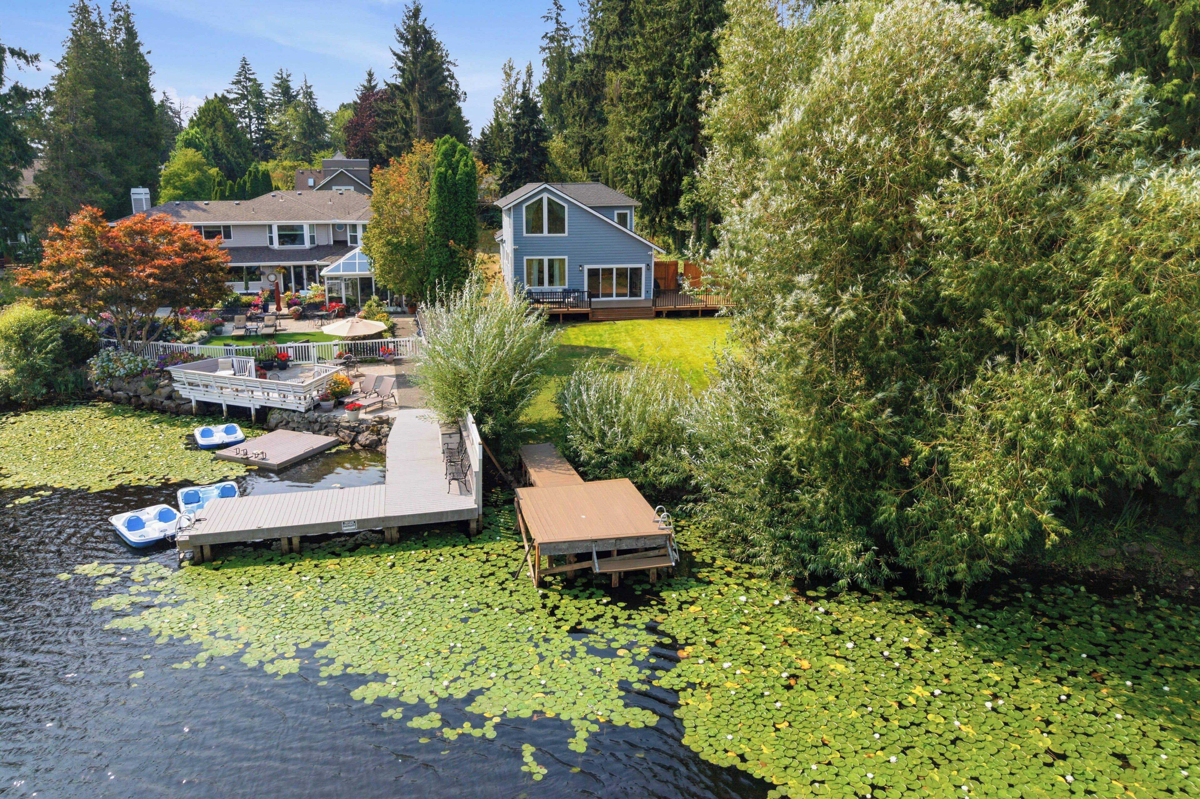 A residential property with a dock, a small boat, and a pond with lily pads.