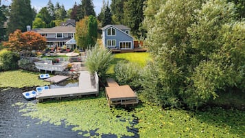 A residential property with a dock, a small boat, and a pond with lily pads.