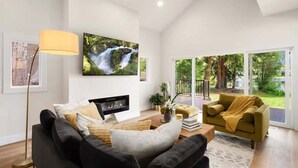 Una sala de estar moderna con chimenea, televisor grande y sofá.