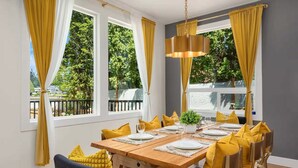 Comedor con mesa de madera para cuatro, cojines amarillos y una lámpara colgante.