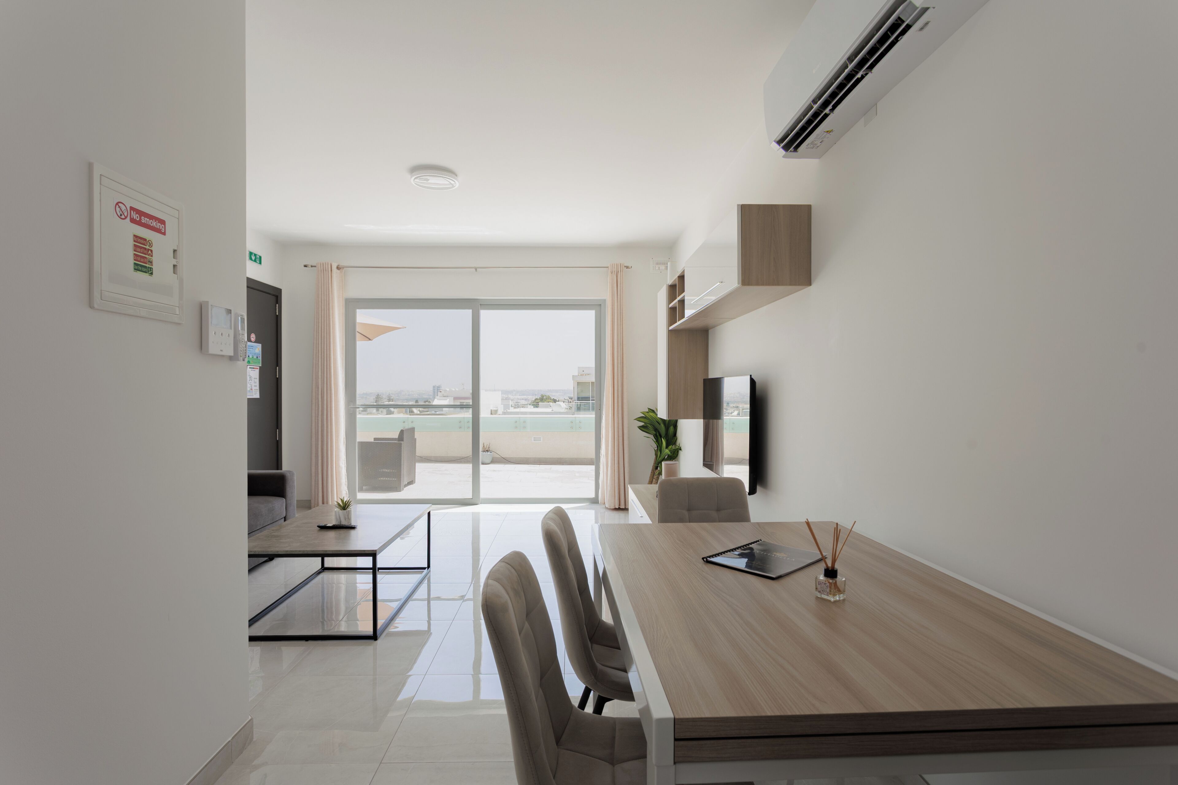Habitación de hotel moderna con zona de comedor, televisión de pantalla plana y vista a la ciudad.