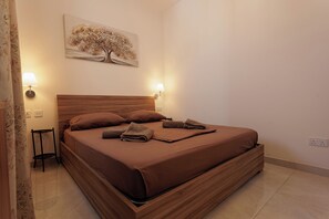 Ein ordentlich bezogenes Bett mit einem hölzernen Kopfteil, zwei Nachttischlampen und einem Baumgemälde an der Wand.
