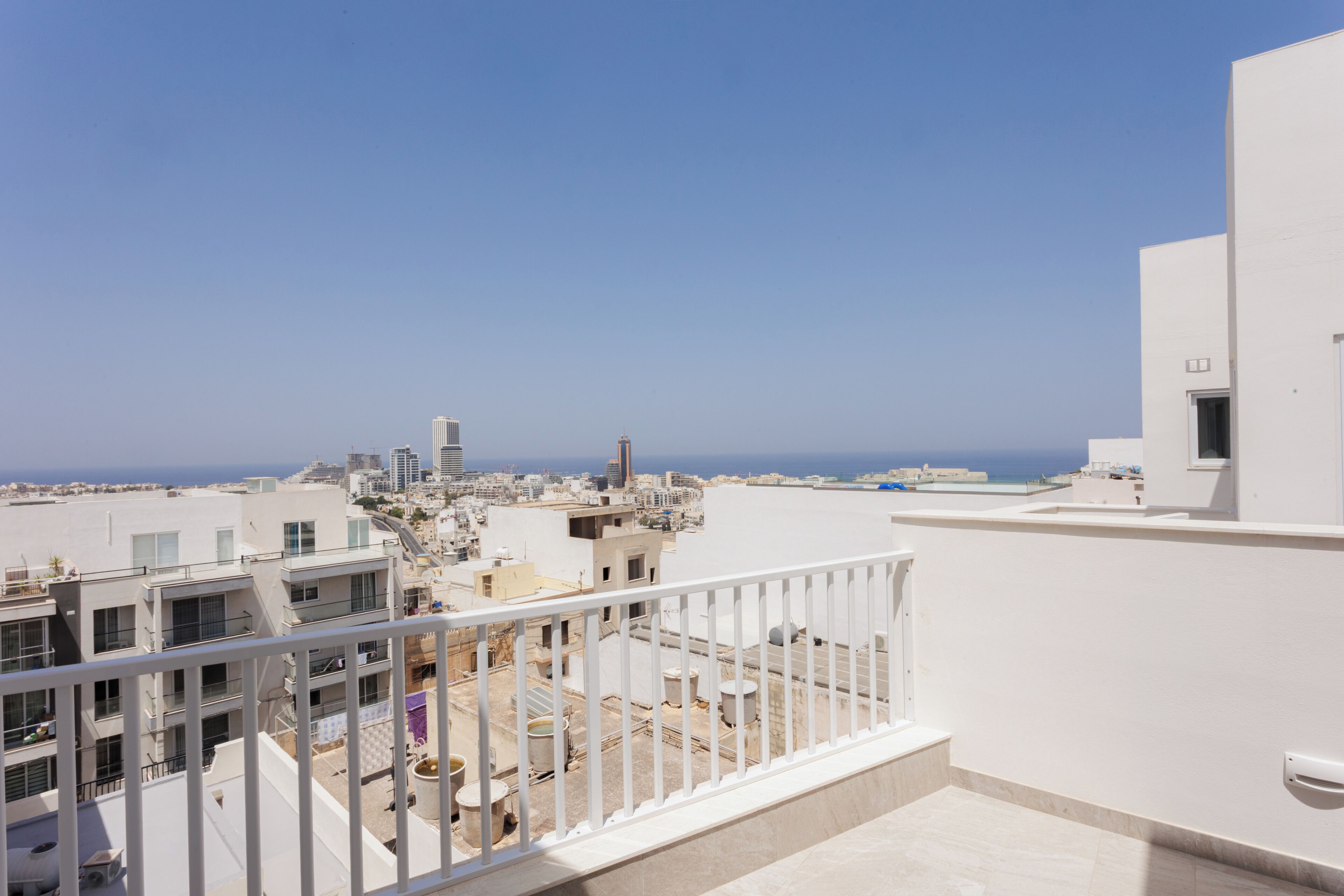 Eine Dachterrasse mit Blick auf eine Stadtlandschaft und das Meer.