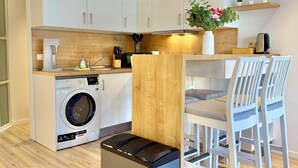 Una cucina funzionale con lavatrice, macchina del caffè e zona pranzo con sedie.
