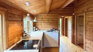 L’intérieur d’une cabane en bois comprend un espace cuisine, des murs en bois et un îlot central.