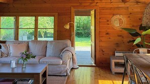 L'intérieur d'un chalet en bois, avec un canapé, une table basse et un coin repas.