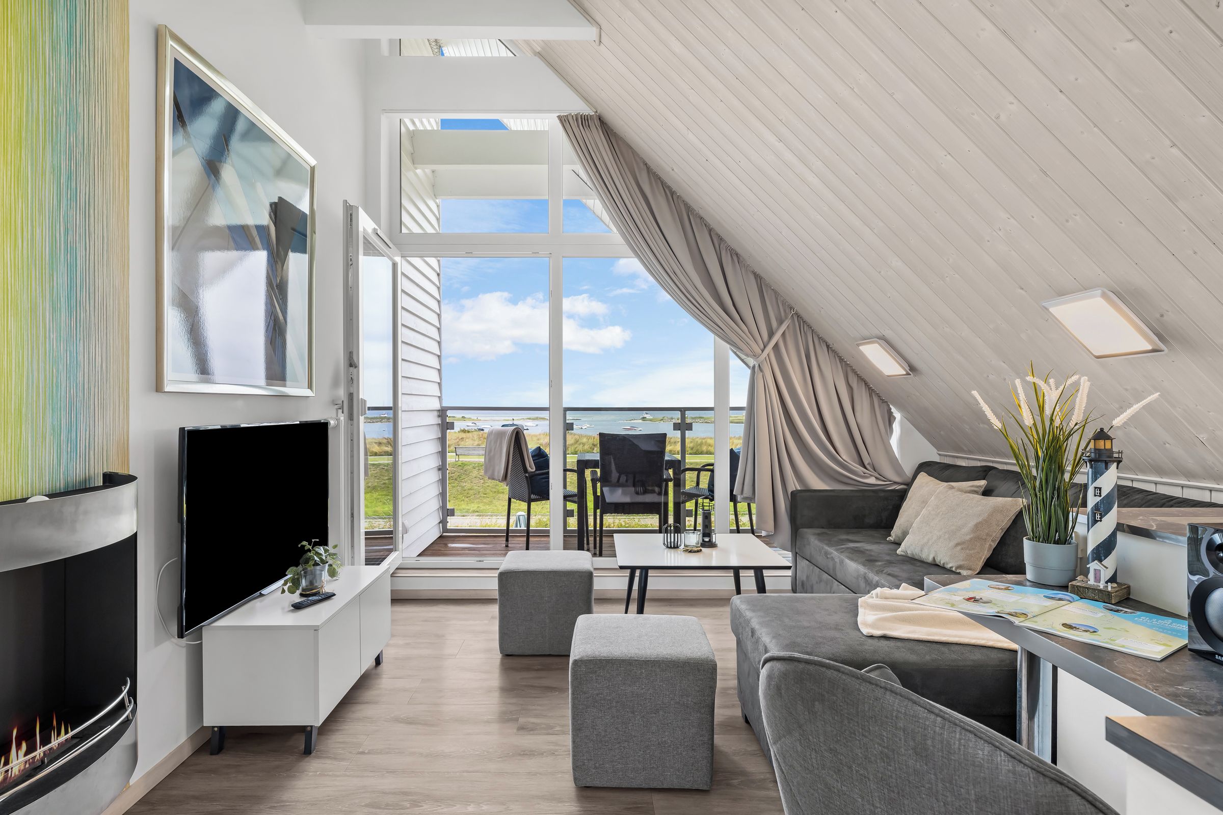 A modern living room with a fireplace, a flat-screen TV, a dining area with a table and chairs, and a sofa.