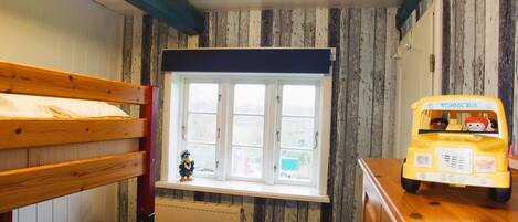 A room with bunk beds, a window with a view, a radiator, and a toy school bus.
