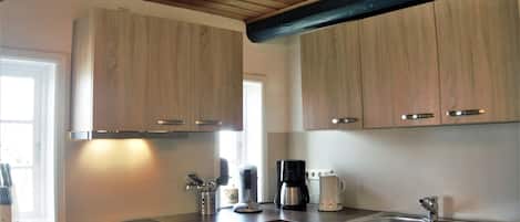 A kitchen with wooden cabinets, stainless steel appliances, and a window providing natural light.
