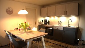 Une cuisine équipée d’une table à manger, de chaises, d’une machine à café, d’une bouilloire et d’un évier.