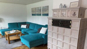 Un salon avec des canapés de couleur turquoise, une table basse en bois et un meuble décoratif orné d’un motif à carreaux.