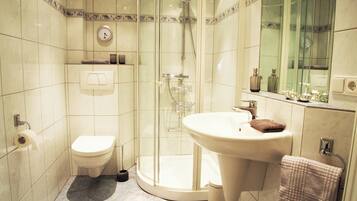 Ein Badezimmer mit Toilette, Waschbecken, Duschkabine und Spiegel.