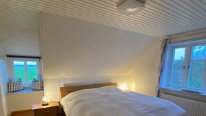 Een slaapkamer met een groot bed, een nachtkastje, een raam met uitzicht en een plafondventilator.