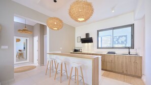 Cozinha moderna com ilha central, banquetas e uma janela ampla.