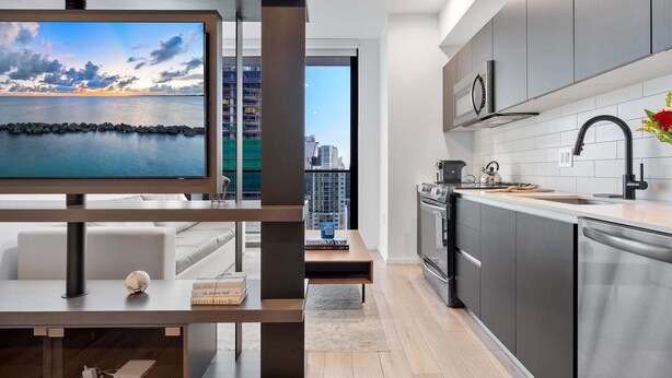 A modern kitchen with a built-in oven, a sink, and a dining area with a table and chairs. - Biscayne Studio EXC Modern Studio in Miami (Miami)