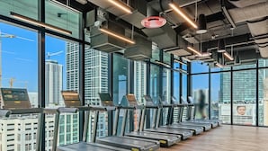 A gym with treadmills aligned along a wall with large windows offering city views. - Biscayne Studio EXC Modern Studio in Miami (Miami)
