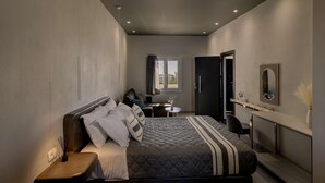 A modern bedroom with a bed, bedside table, and a desk with a chair. - Sunset Studio Seaview - Nea Premium Residences (Santorini)