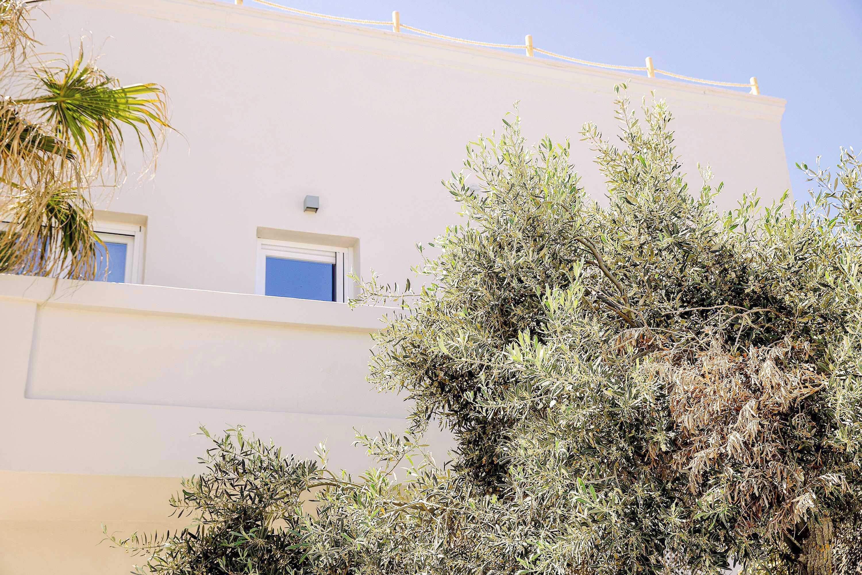 Un edificio con fachada blanca, un balcón y una ventana.