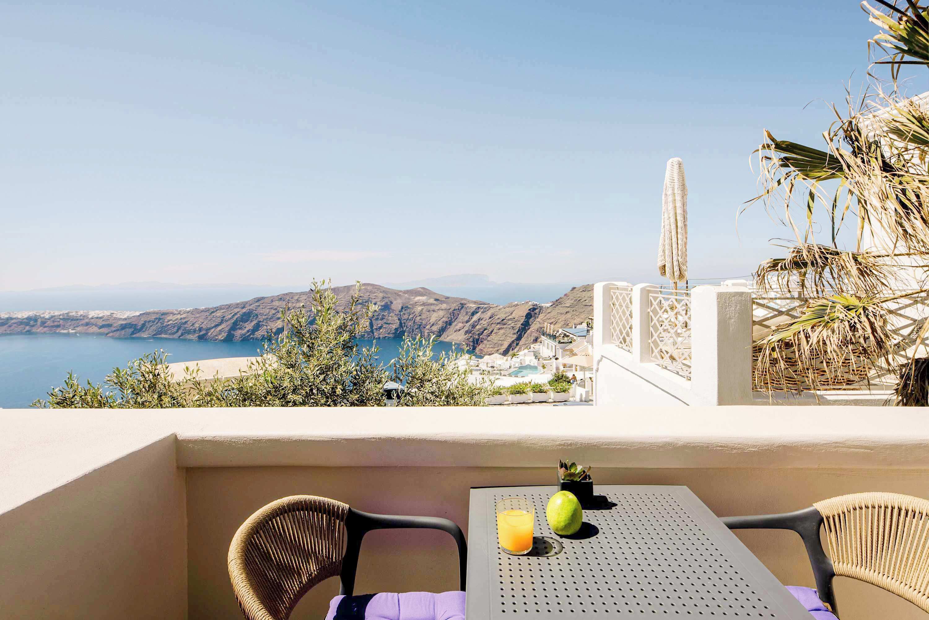 Un balcón con mesa, sillas y vista a un paisaje costero.