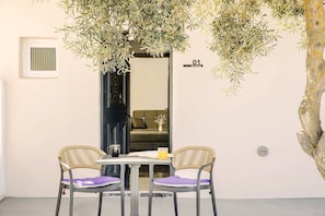 Una habitación con una mesa, dos sillas de mimbre, un espejo y una puerta con el número.