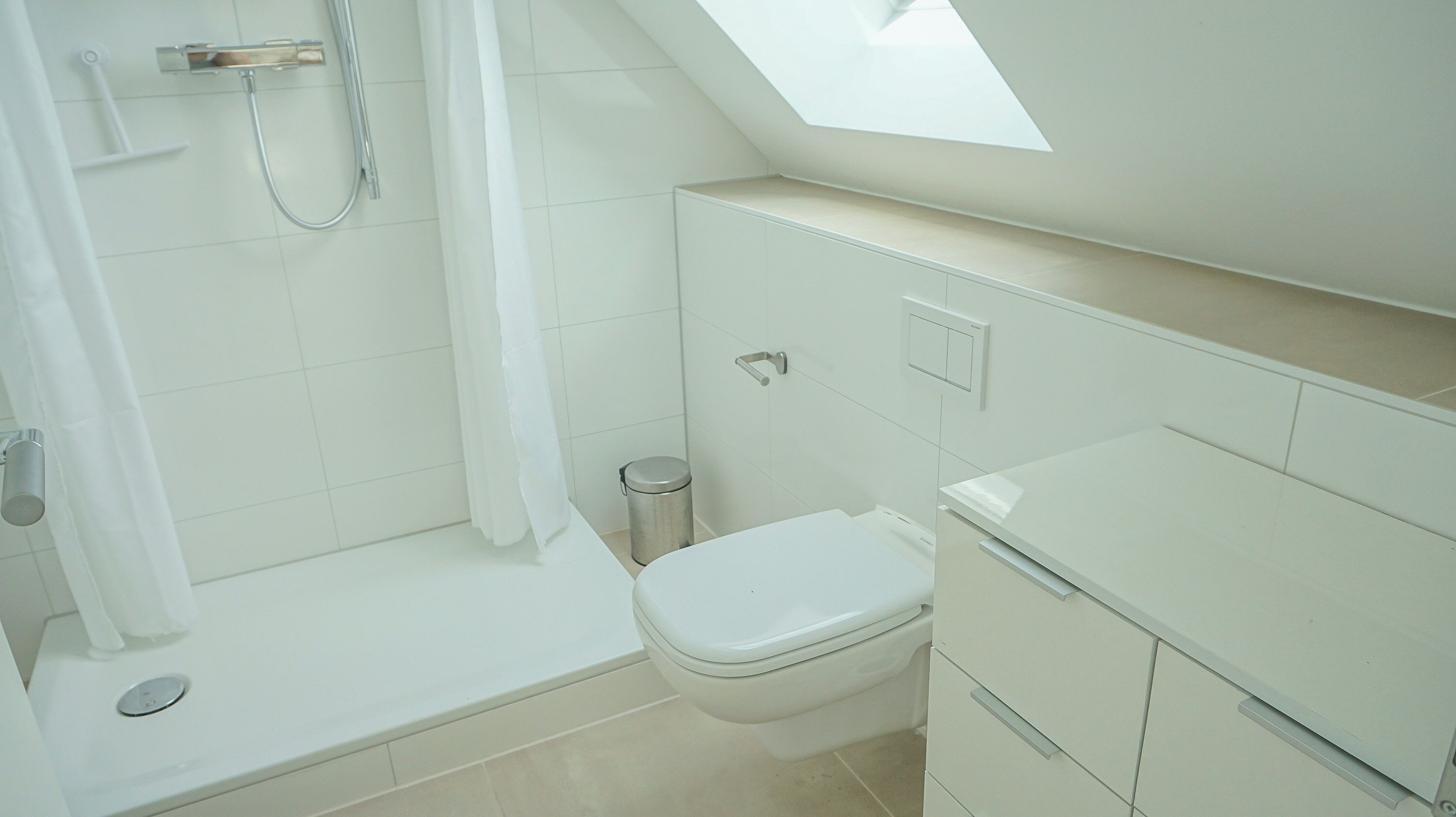Une salle de bain avec douche, toilettes et lavabo.