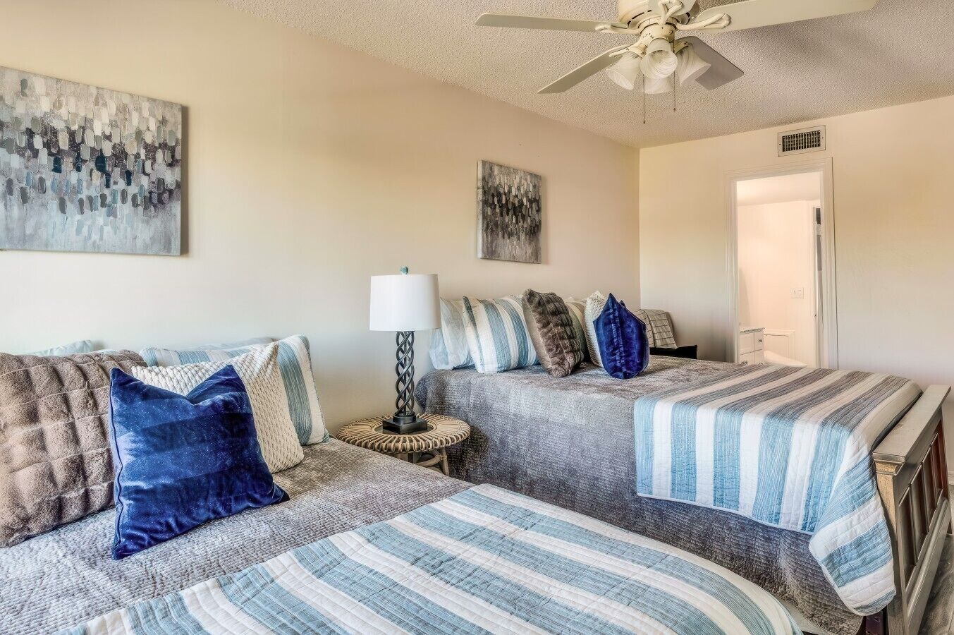A room with two beds, a ceiling fan, and a door.