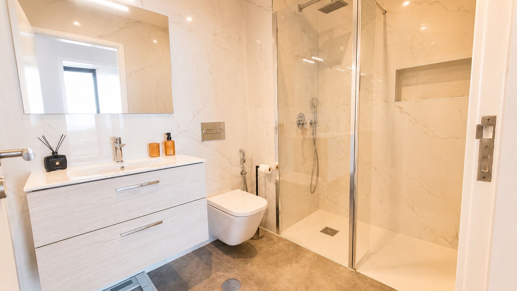 A modern bathroom with a glass-enclosed shower, a white toilet, and a vanity with drawers and a mirror.