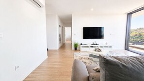 A modern living room with a flat-screen TV, a sofa, and a coffee table. - Vanguard View Apartment (Câmara de Lobos)