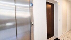 A modern elevator with a metallic finish and a blue accessibility sign. - Vanguard View Apartment (Câmara de Lobos)
