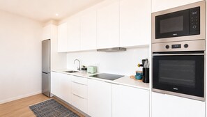 A modern kitchen with white cabinets, a stainless steel refrigerator, a microwave, and an oven. - Vanguard View Apartment (Câmara de Lobos)