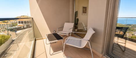 A balcony with two chairs and a small table, overlooking a cityscape.