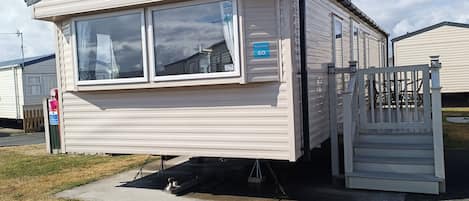 A mobile home with a sliding door, a small porch, and a number sign indicating unit 60.