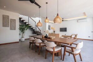 A spacious dining area with a wooden table and chairs, a staircase, and pendant lighting. - Brand New 4br Villa, Close to nature (Canggu)