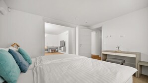 Een moderne hotelkamer met een groot bed, een bureau en uitzicht op een andere kamer.
