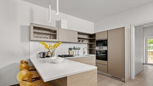 Een moderne keuken met een centraal eiland, houten stoelen en inbouwapparatuur.