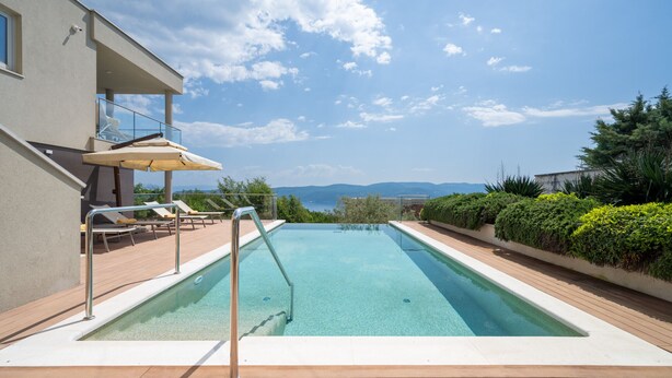 A swimming pool with a wooden deck, lounge chairs, and a view of the sea. - Pedacito de Cielo 1 BDR Sew View apartment & pool (Zagorje)